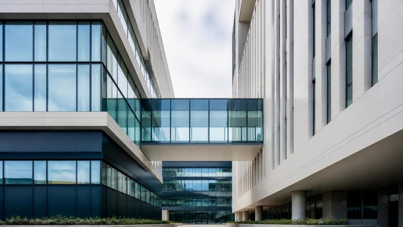Two glass-and-concrete structures meeting through a clean junction