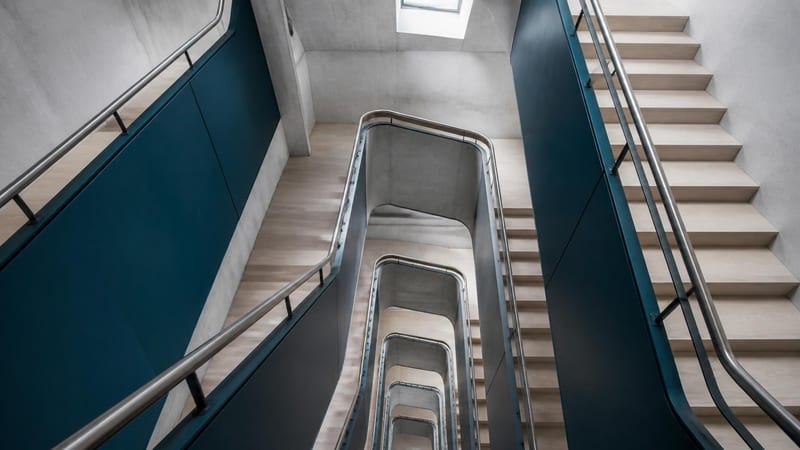 A modern staircase of repeating flights in concrete and pale timber